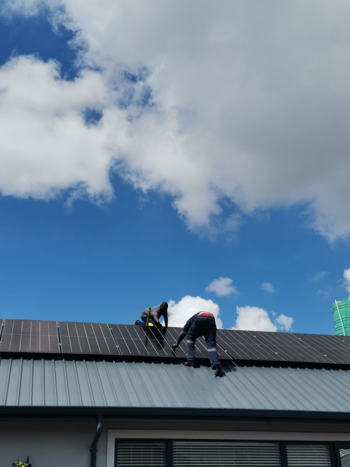 Installer fixing mounting rails on a metal sheet roof