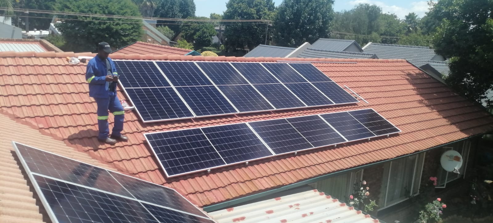 Installer working on a solar array on a tiled roof
